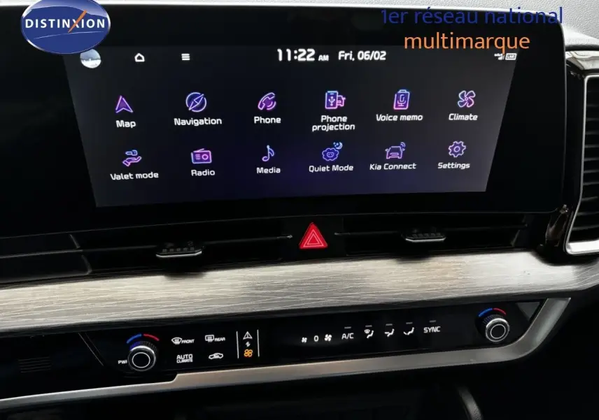 Vue rapprochée de l’écran tactile et de la console centrale du Kia Sportage blanc nacré, affichant les commandes multimédias et climatiques.