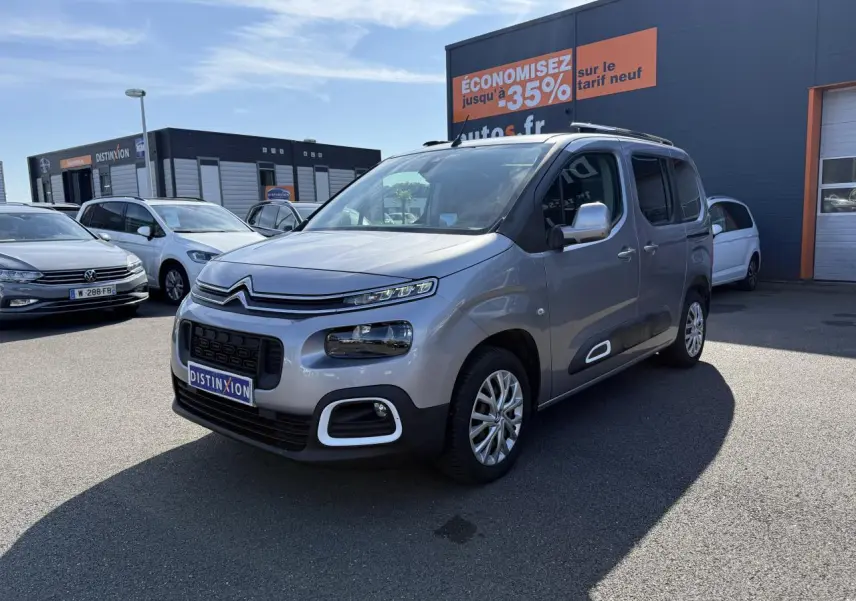 Citroën Berlingo gris foncé vu en 3/4 avant droit, avec ses phares distinctifs et coques de rétroviseurs ton caisse.