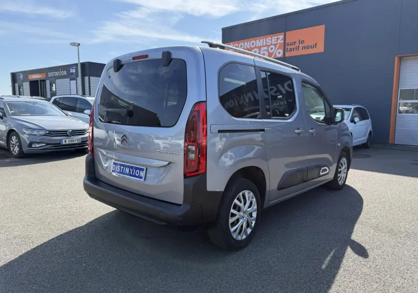 Vue 3/4 arrière droite d'un Citroën Berlingo gris foncé avec vitres arrière surteintées sur parking.