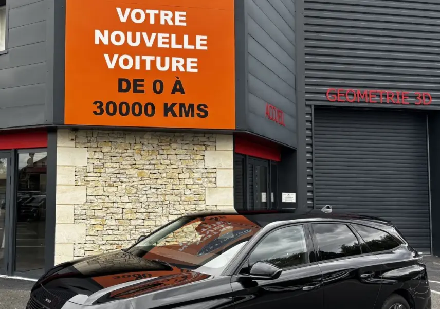 Peugeot 308 PureTech 130 noire vue en 3/4 avant droit devant un bâtiment avec panneau orange Distinxion.