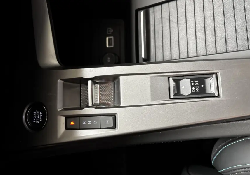 Vue rapprochée de la console centrale argentée avec bouton start, sélecteur de boîte auto et commande Drive Mode d'une Peugeot 308 noire.