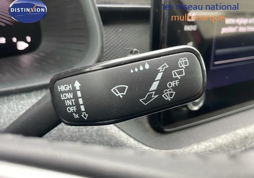 Gros plan sur la commande des essuie-glaces du Skoda Kamiq 2024, avec tableau de bord et écran tactile en arrière-plan.