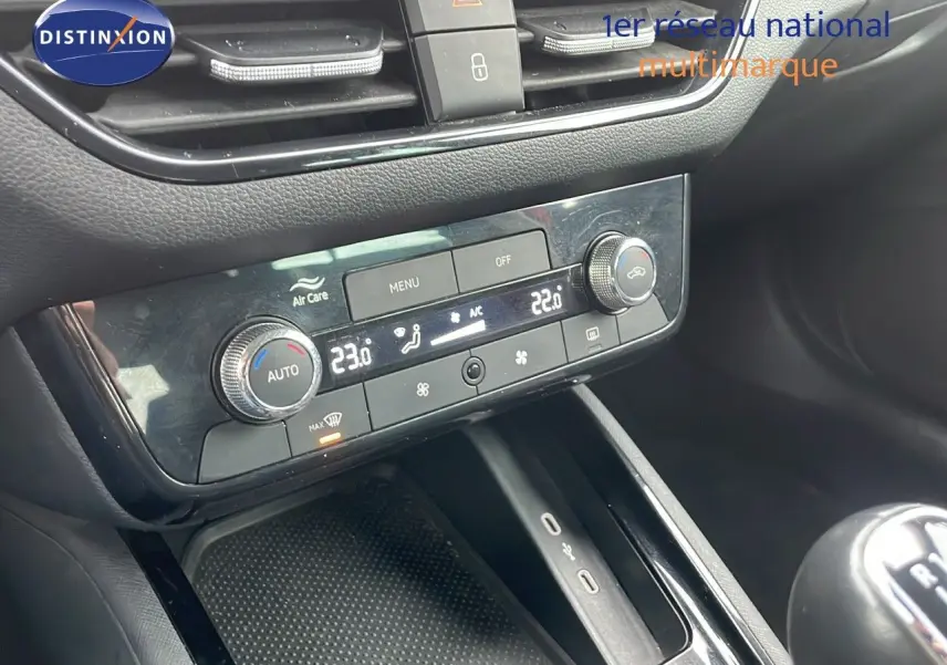 Gros plan sur la console centrale noire avec climatisation digitale et levier de vitesse manuelle d'un Skoda Kamiq rouge.