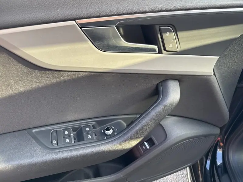 Intérieur côté gauche de la porte avant noire brillante d'une Audi A4 Avant 30 TDI, avec commandes de vitres et verrouillage.