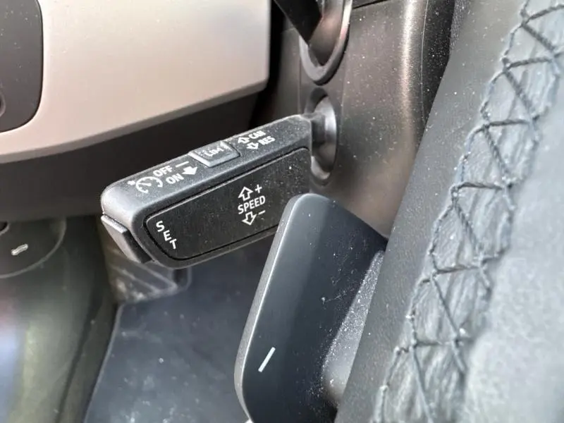 Gros plan sur la commande de régulateur de vitesse noire à gauche du volant cuir d'une Audi A4 Avant noir brillant.