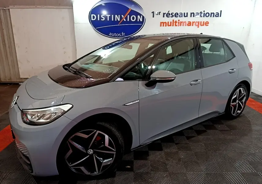 Vue 3/4 avant droit d'une Volkswagen ID.3 77 kWh Pro S gris foncé en intérieur, avec jantes distinctives et logo visible.