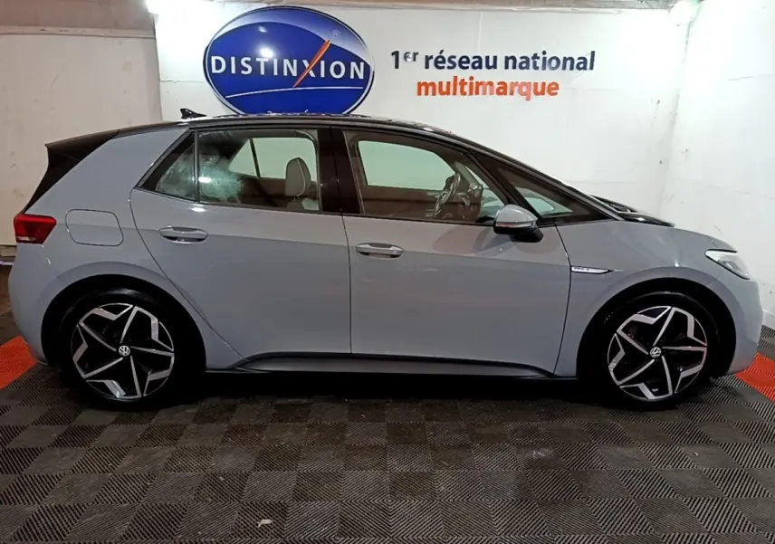 Vue de profil côté gauche d'une Volkswagen ID.3 gris foncé avec jantes noires et argentées dans un garage.