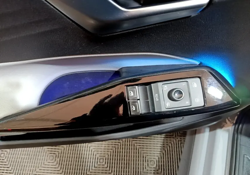 Gros plan sur la commande des rétroviseurs et vitres côté conducteur du Volkswagen ID.3 gris foncé avec éclairage d’ambiance bleu.