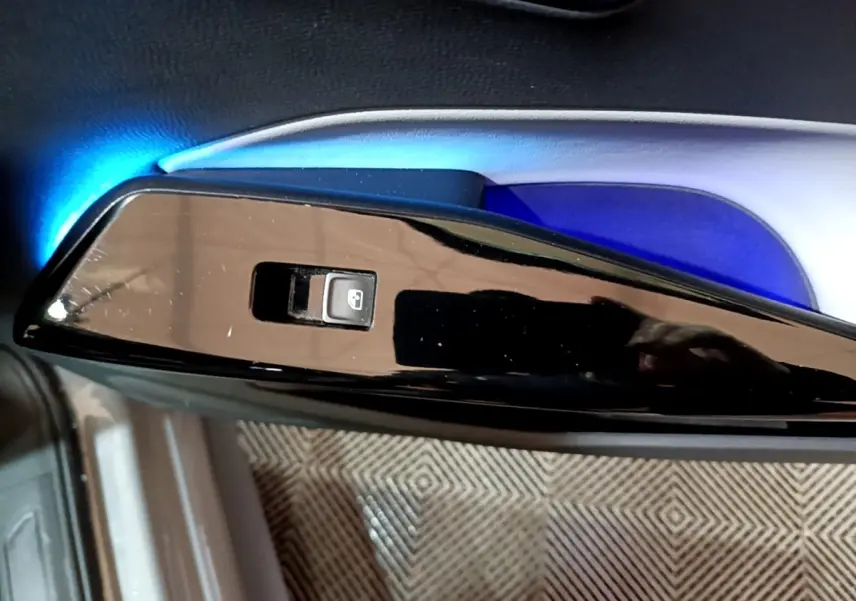 Gros plan sur l'interrupteur de lève-vitre côté conducteur du Volkswagen ID.3 77 kWh Pro S gris foncé, éclairage bleu intérieur.