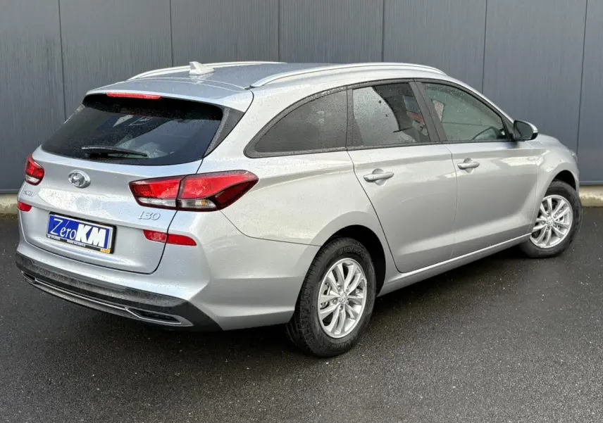 Vue 3/4 arrière droite d'une Hyundai i30 SW T-GDI 120 gris argent métallisé avec vitres arrière surteintées et jantes alliage.