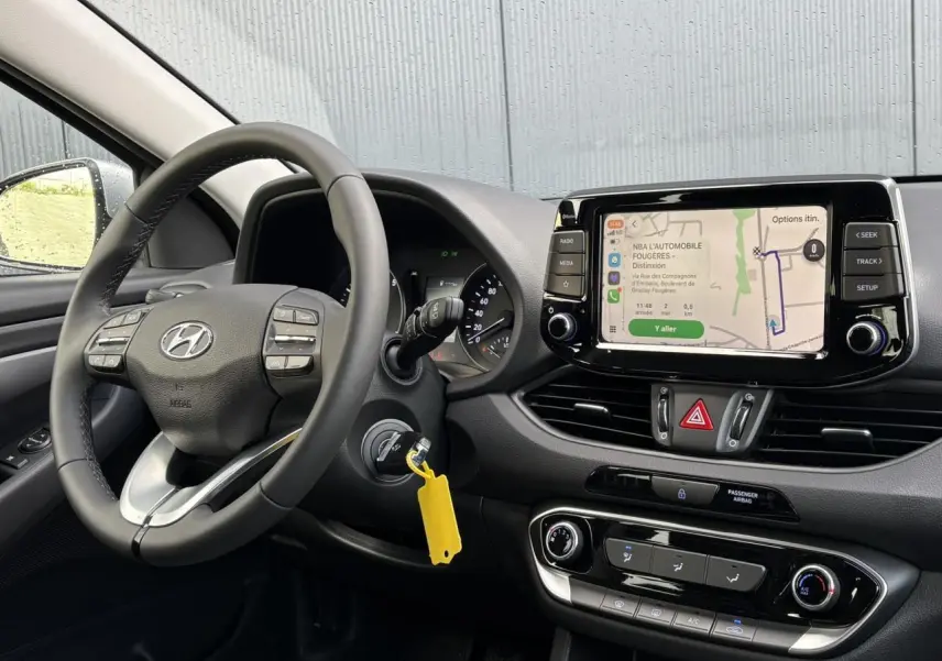 Vue intérieure côté conducteur du tableau de bord de la Hyundai i30 SW gris argent avec écran tactile et volant cuir.
