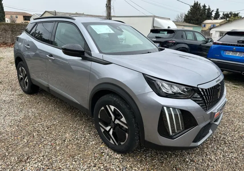 Peugeot 2008 Hybrid gris en 3/4 avant droit, avec barres de toit et jantes alliage 17 pouces visibles.