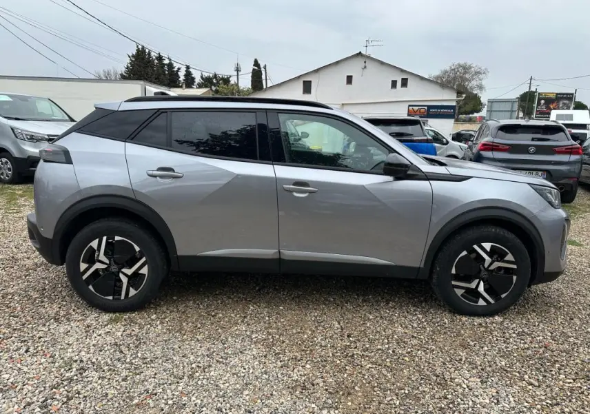 Peugeot 2008 Hybrid gris vue de profil côté gauche, avec barres de toit et jantes alliage 17 pouces.