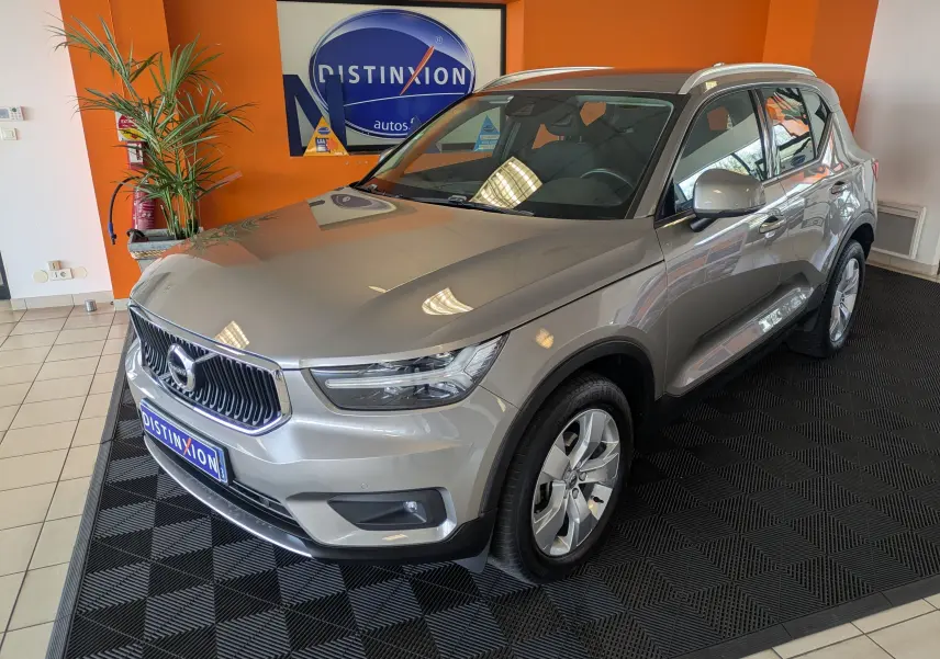 Vue 3/4 avant droite d'un Volvo XC40 marron clair en showroom avec jantes alliage et toit panoramique.