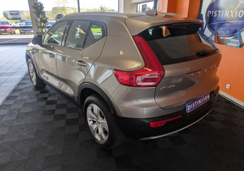 Vue 3/4 arrière droite d’un Volvo XC40 marron clair Momentum 2WD 2021, avec feux arrière caractéristiques et toit noir.