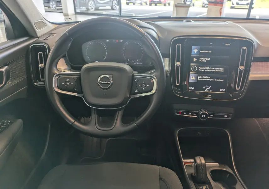 Vue intérieure centrée sur le volant noir d'un Volvo XC40 2021 avec écran tactile et tableau de bord numérique.