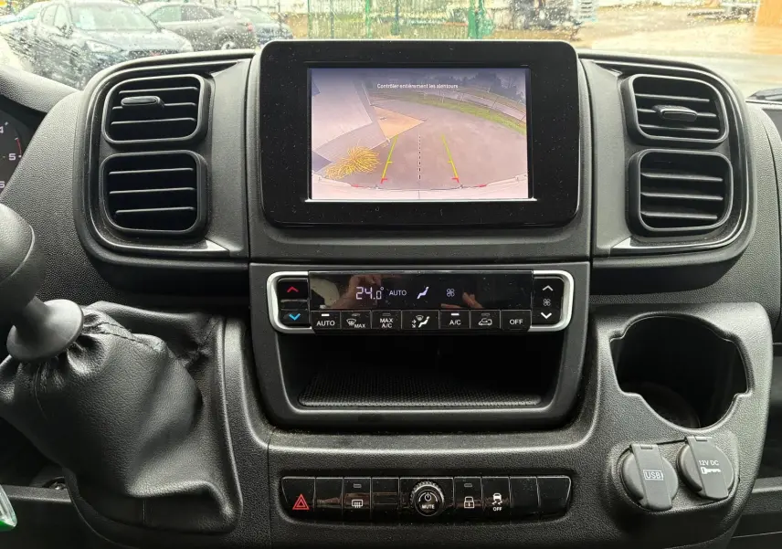 Vue rapprochée du tableau de bord noir du Fiat Ducato 2023 avec écran de caméra de recul et commande de climatisation.