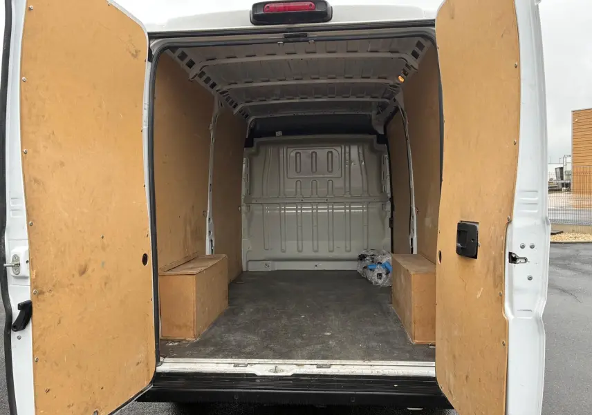 Vue arrière ouverte du fourgon blanc FIAT Ducato 2023, montrant l'intérieur vide avec parois en bois.