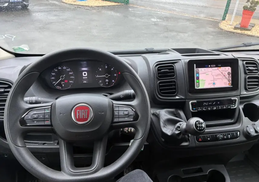 Vue intérieure du tableau de bord du Fiat Ducato Fourgon 2023, volant multifonction et écran tactile avec navigation.