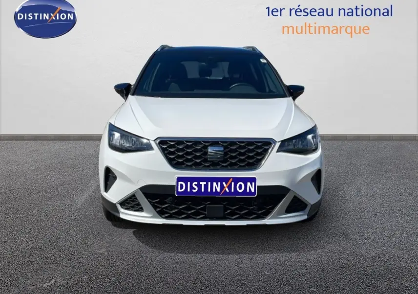 Vue frontale d'un SEAT Arona blanc avec toit noir, calandre noire et phares LED allumés.