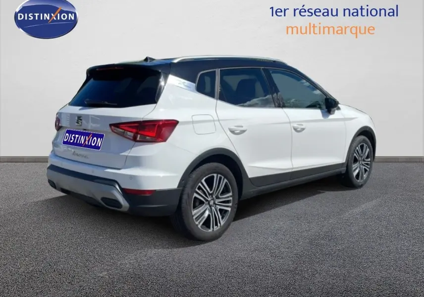 Vue 3/4 arrière droite d'un SEAT Arona blanc avec toit noir, jantes alliage et vitres teintées.