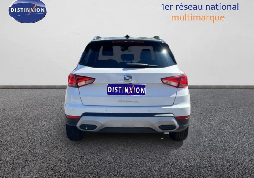 Vue arrière d'un SEAT Arona blanc avec toit noir, montrant les feux arrière et le pare-chocs arrière distinctif.