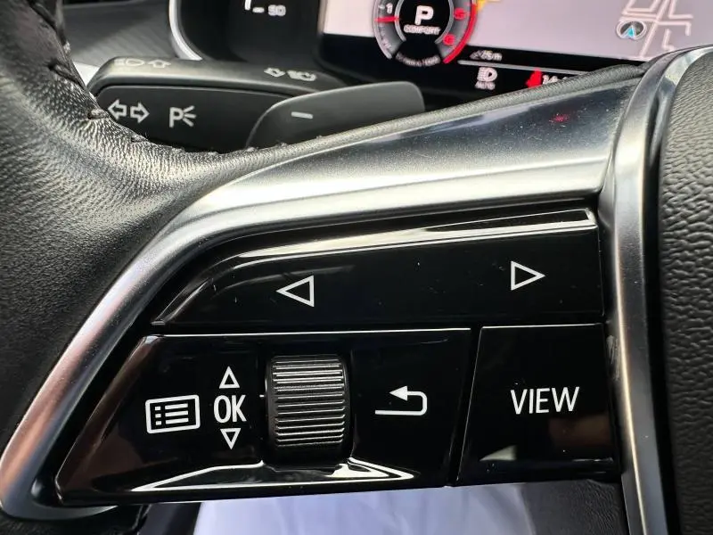 Gros plan sur les commandes noires du volant multifonction de l'Audi A6 Avant 45 TDI S line de 2019.