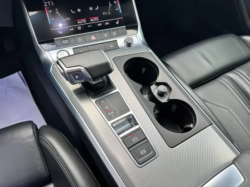Gros plan sur la console centrale de l'Audi A6 Avant noire, avec levier de vitesses automatique et sièges cuir noir.