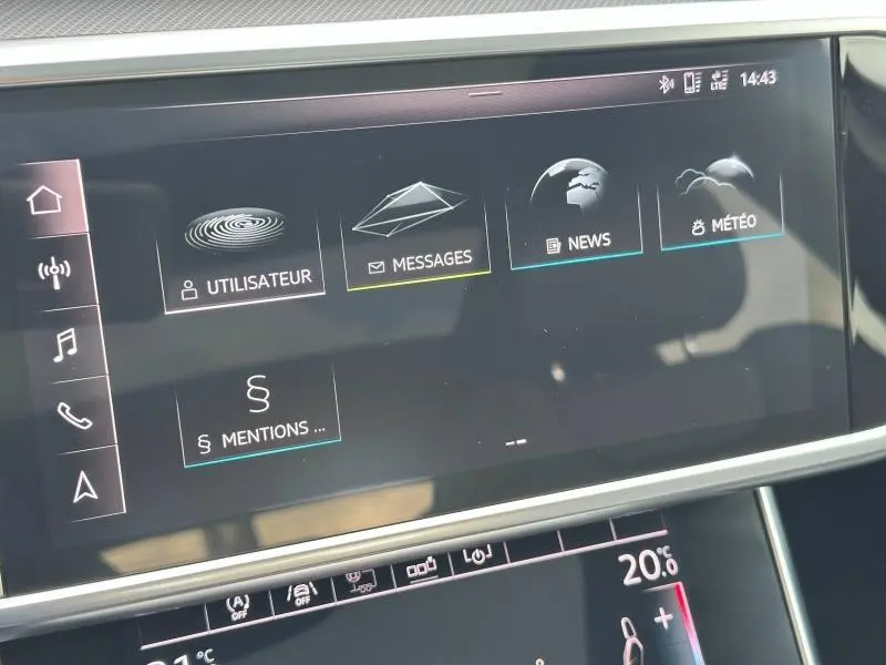 Écran tactile central de l'Audi A6 Avant noir métal affichant les menus messages, météo et utilisateur.