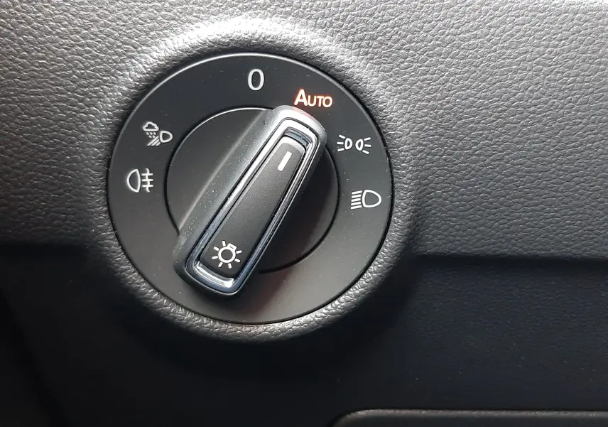 Commande de réglage des phares en mode automatique sur le tableau de bord noir du Volkswagen T-Roc gris Indium 2024.