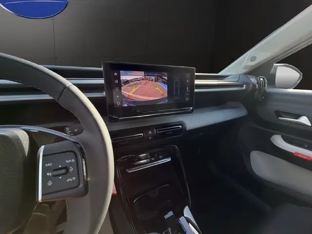 Vue intérieure côté conducteur du tableau de bord gris clair du Citroën C3 Aircross hybride avec écran tactile affichant la caméra de recul.