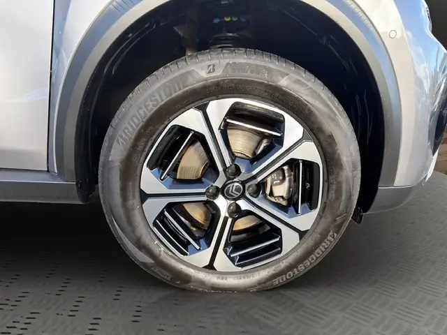 Gros plan sur la roue avant droite d'une Citroën C3 Aircross hybride gris foncé avec jante alliage bicolore moderne.