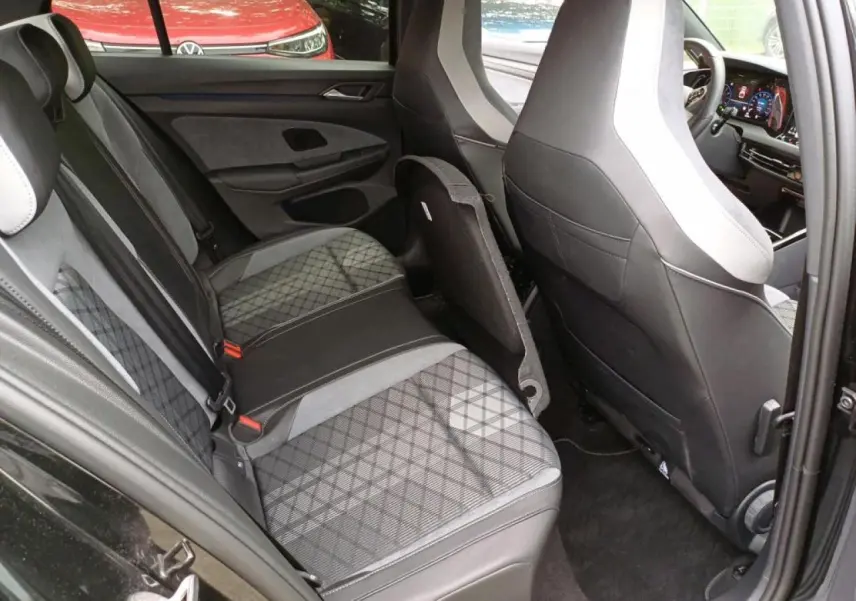 Vue intérieure côté gauche sur la banquette arrière et les sièges avant en tissu noir et gris de la Volkswagen Golf VIII R-Line.