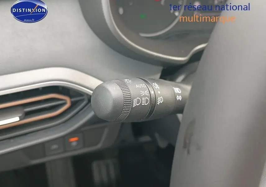 Gros plan sur la commande des phares à gauche du volant dans l'habitacle de la Dacia Sandero noire 2025
