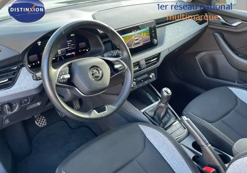Intérieur avant droit du Skoda Kamiq 2024 gris graphite, volant multifonction, écran tactile et boîte manuelle visible.