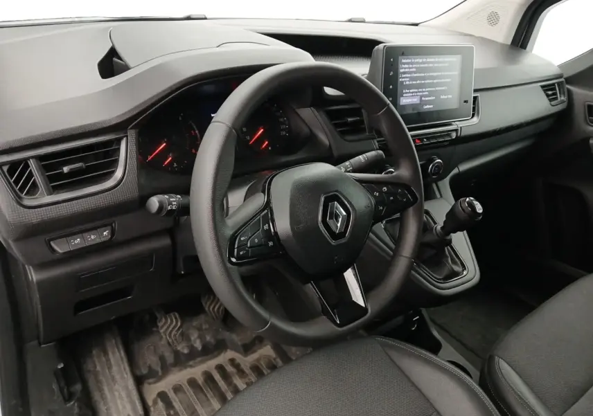 Vue intérieure côté conducteur du Renault Kangoo 2024, volant multifonction, levier de vitesse manuel et écran tactile central visible.