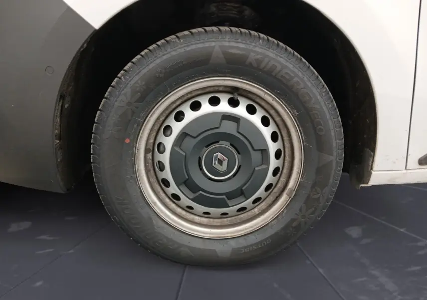 Gros plan sur la roue avant droite du Renault Kangoo blanc 2024 avec jante acier et logo Renault central.