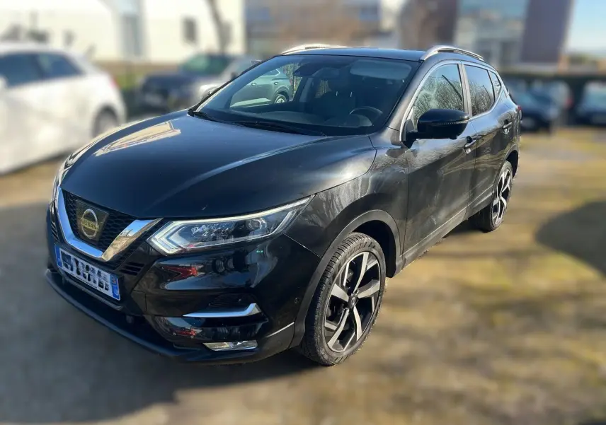 Nissan Qashqai noir vu en 3/4 avant droit, avec jantes alliage et barres de toit visibles.