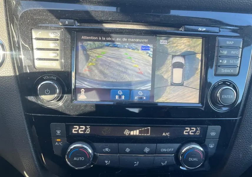 Vue rapprochée de l’écran tactile du Nissan Qashqai noir montrant la caméra de recul et les commandes de climatisation à 22°C.