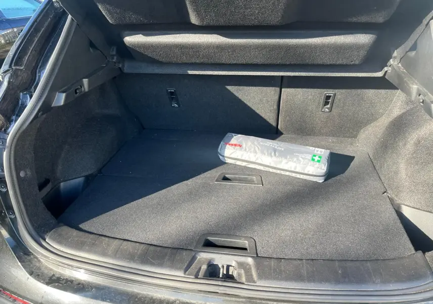 Coffre ouvert vu de l'arrière d'un Nissan Qashqai noir avec trousse de secours Nissan posée à l'intérieur.