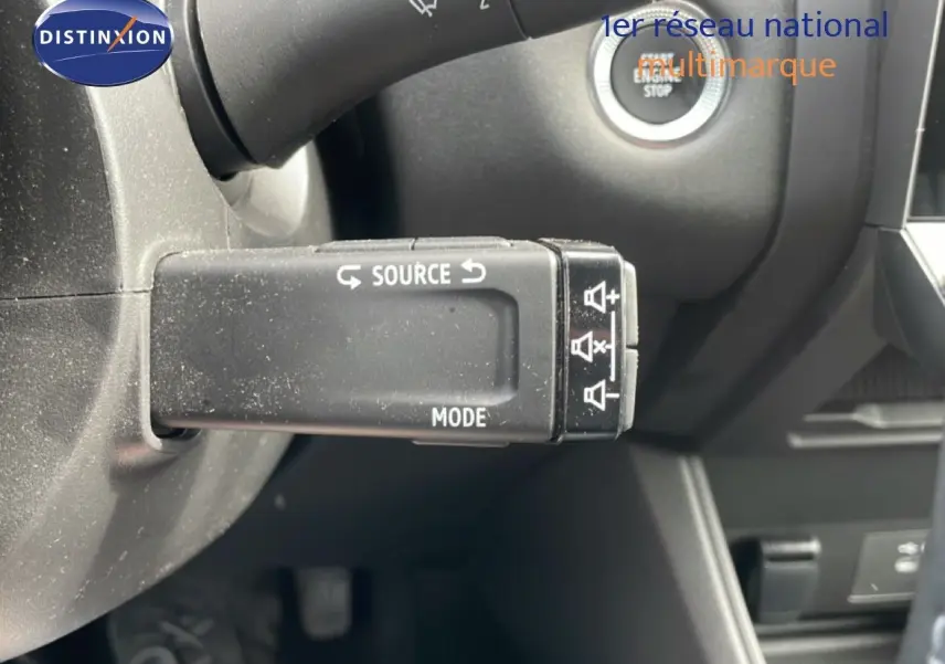 Gros plan sur la commande au volant du Renault Captur 2025, avec bouton source et mode, intérieur gris noir.
