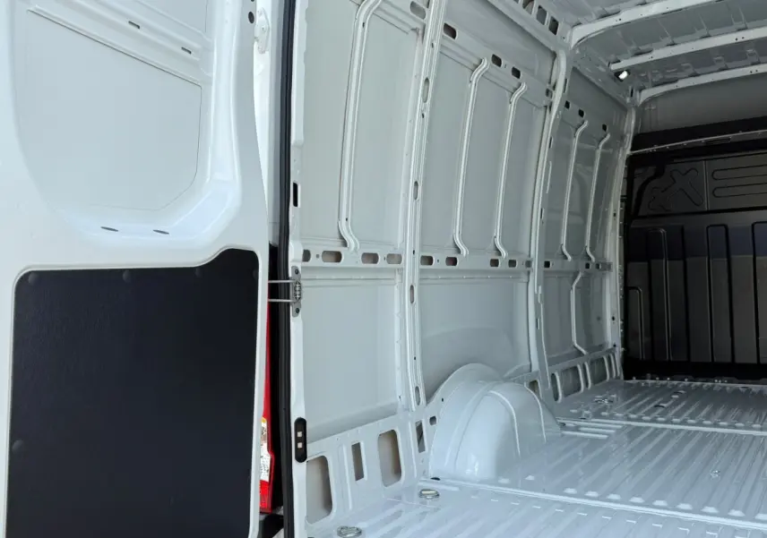 Vue intérieure arrière du fourgon Iveco Daily blanc 2026, montrant l'espace de chargement vide et les parois métalliques.