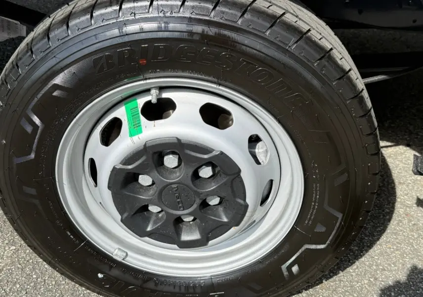 Gros plan sur la roue avant droite du Iveco Daily 2.3 35S16 V12 blanc avec jante acier et pneu Bridgestone.