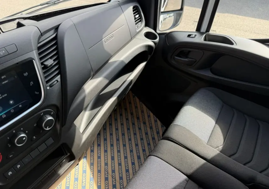 Vue intérieure côté passager de l'IVECO Daily blanc 2026, montrant tableau de bord et siège tissu gris.