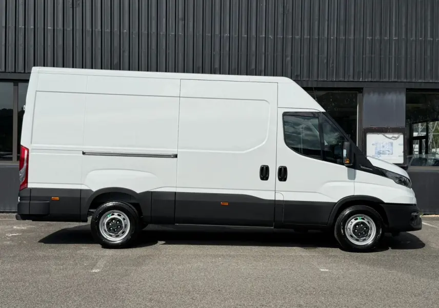 Fourgon Iveco Daily blanc vu de profil côté gauche, avec bas de caisse noir et porte coulissante latérale.