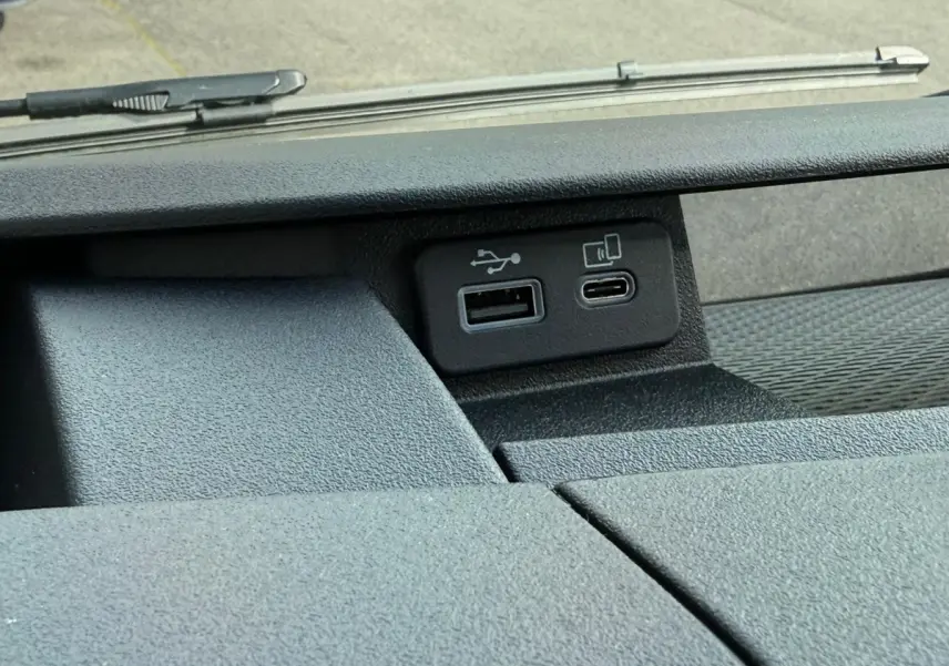 Gros plan sur les ports USB et USB-C du tableau de bord noir du Iveco Daily blanc 2026, vue intérieure frontale.