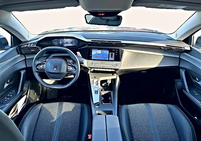 Vue intérieure avant de la Peugeot 308 2025, tableau de bord moderne avec écran tactile et volant multifonction noir.