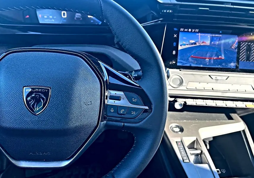 Vue intérieure centrée sur le volant multifonction Peugeot 308 gris selenium avec écran tactile affichant la caméra de recul.