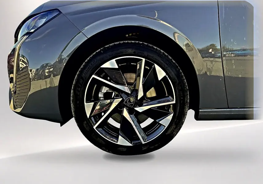 Gros plan sur la roue avant gauche et une partie de la carrosserie gris selenium de la Peugeot 308 2025.