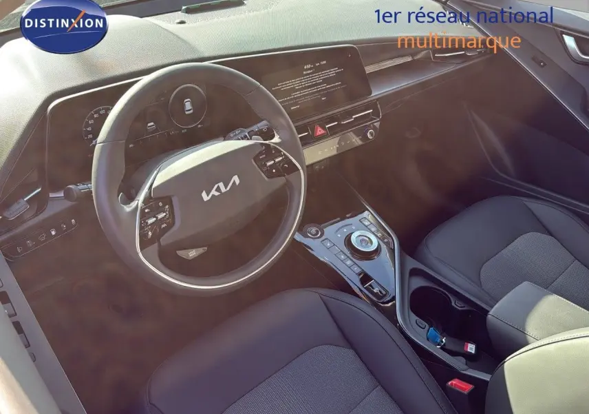 Vue intérieure du poste de conduite du Kia Niro 2025, volant multifonction et console centrale moderne en cuir noir.